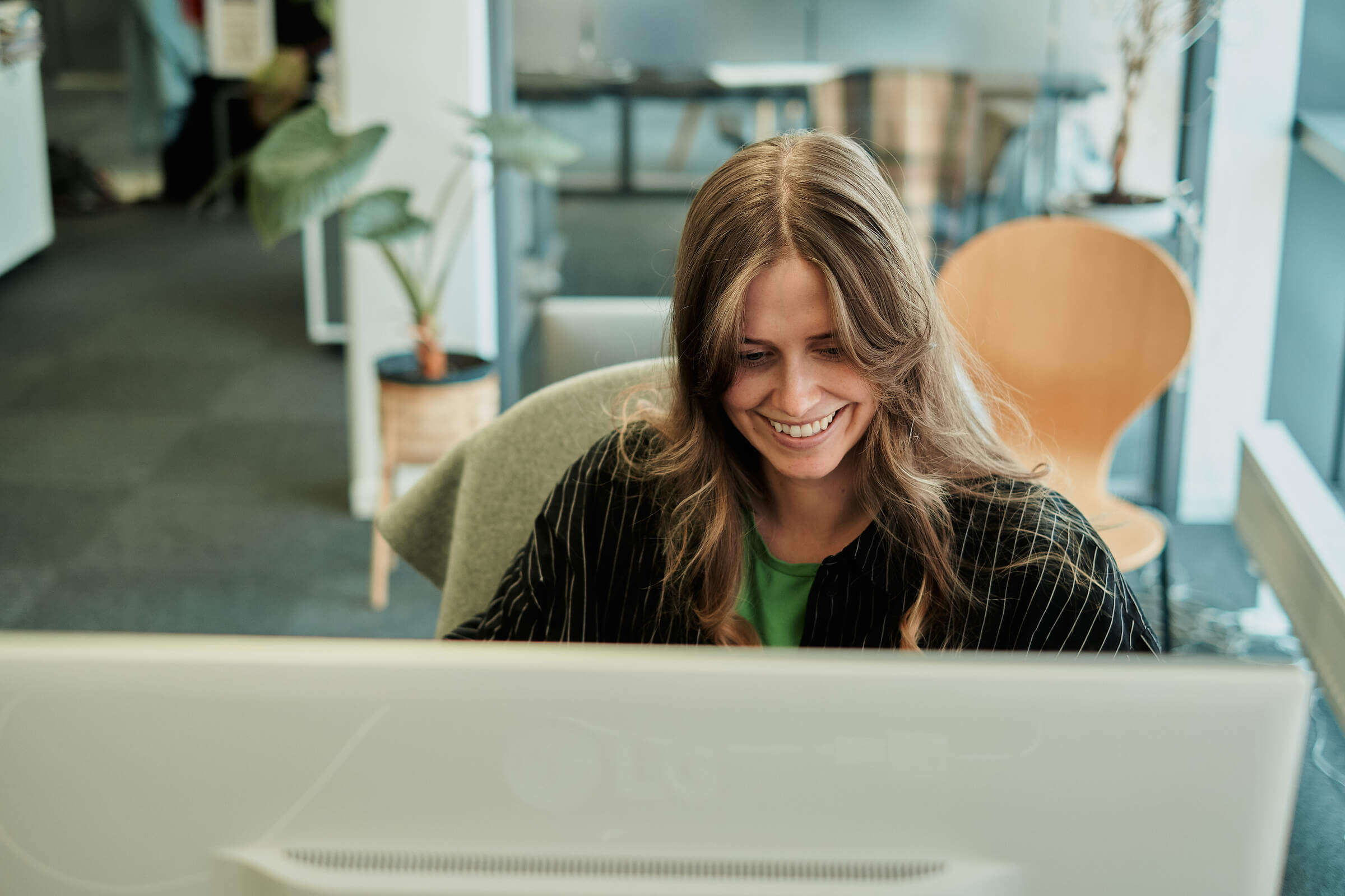 Charlotte hos Aptum smiler foran skjermen